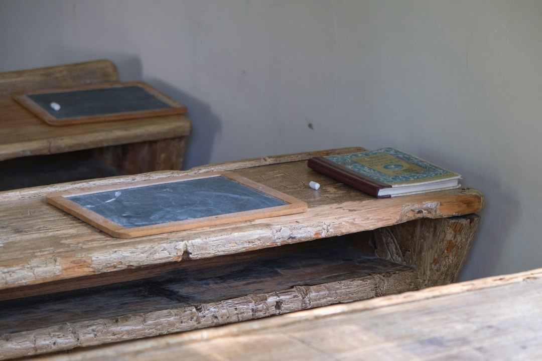 Rustic wooden school desks with slates, chalk, and a book