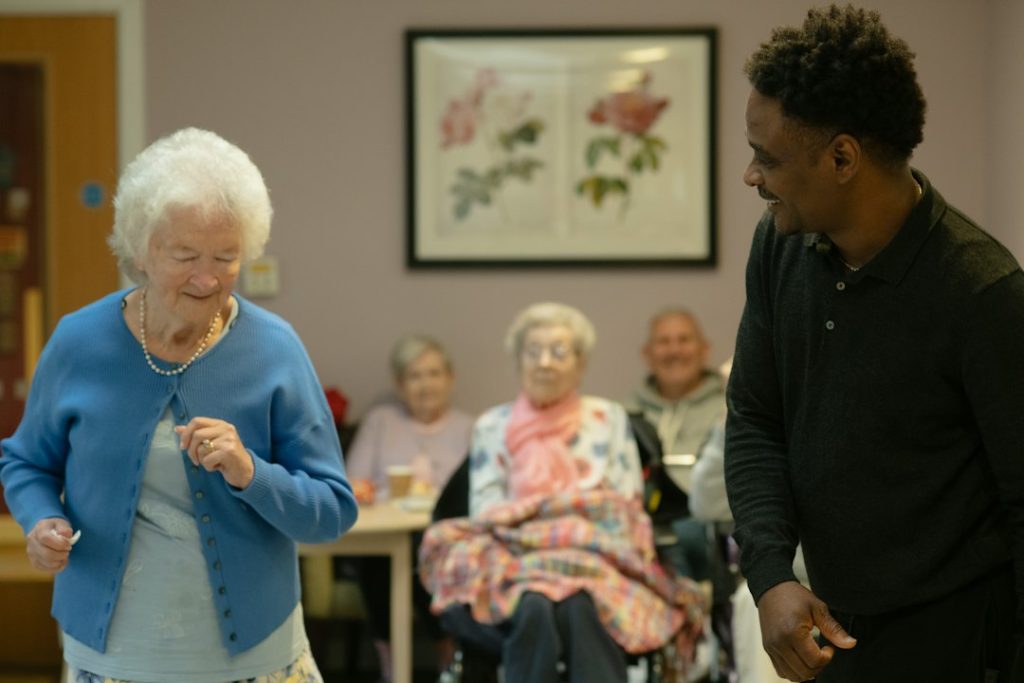 Elderly woman dances with caregiver in a community room