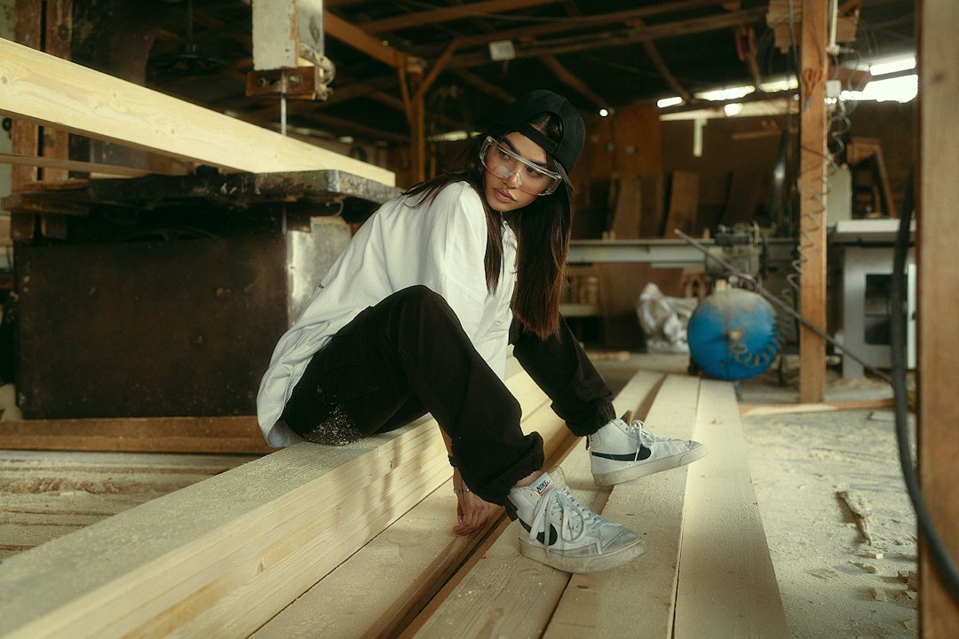 Young woman sitting on lumber in workshop
