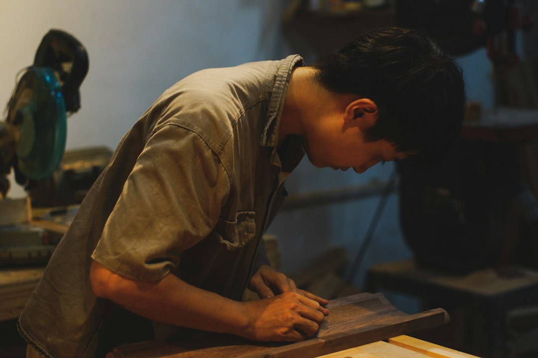Man sanding a wooden plank in a workshop