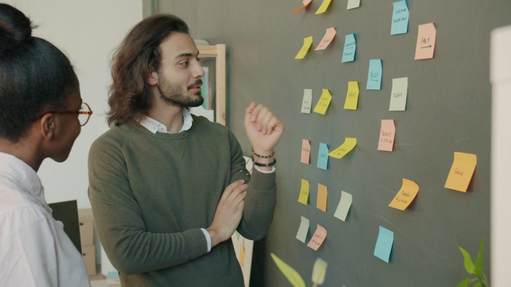 Two colleagues discussing ideas on a sticky note wall