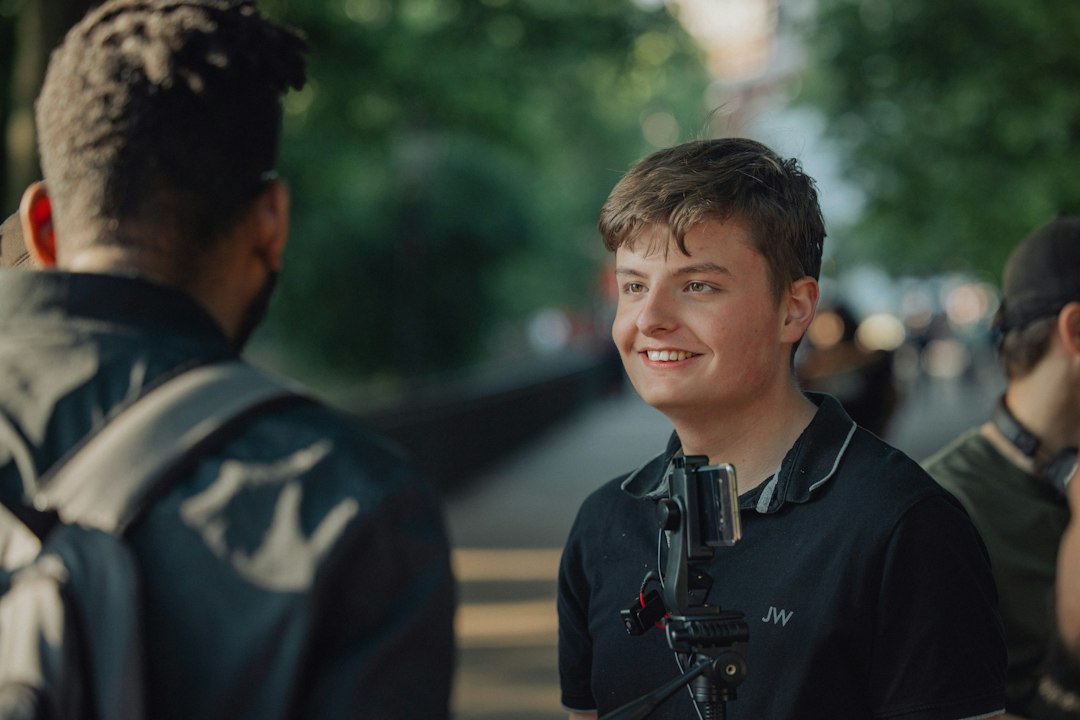 A young man smiles while talking with another