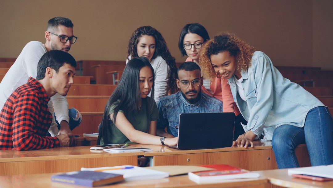 Diverse group of students gathered around laptop
