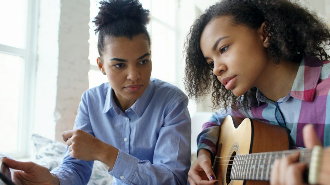 Two young women learning to play guitar together
